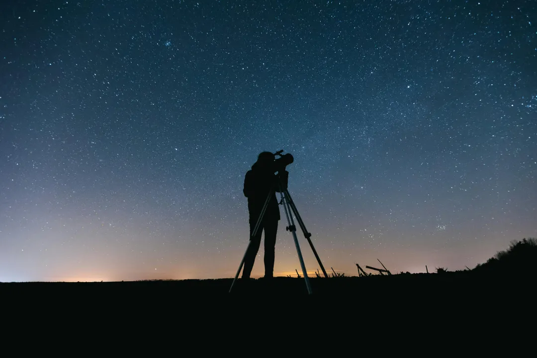 Stargazer using a telescope under a starry sky